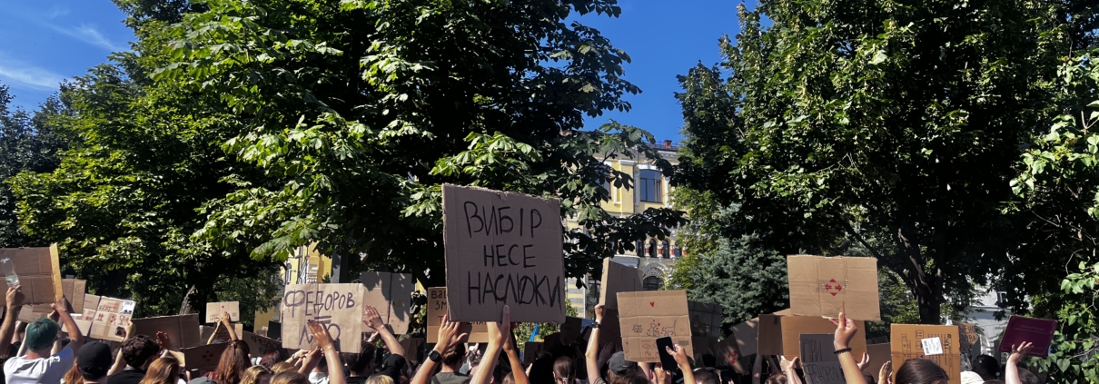 Manifestanti a Kyiv con cartelli di cartone, tra cui «la scelta porta conseguenze», durante le proteste per la reintegrazione di Mykhailo Fedorov, 16 luglio 2026